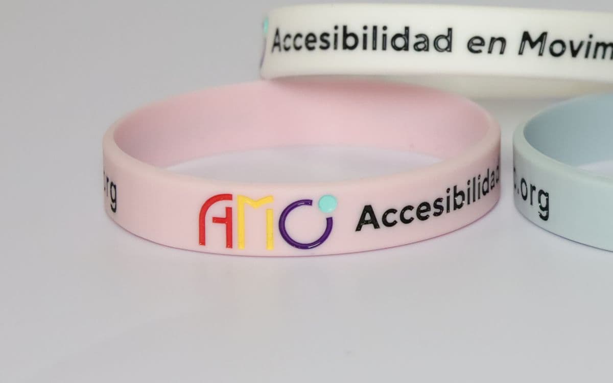 Pulsera rosa de AMO con el logotipo y el texto Accesibilidad en Movimiento